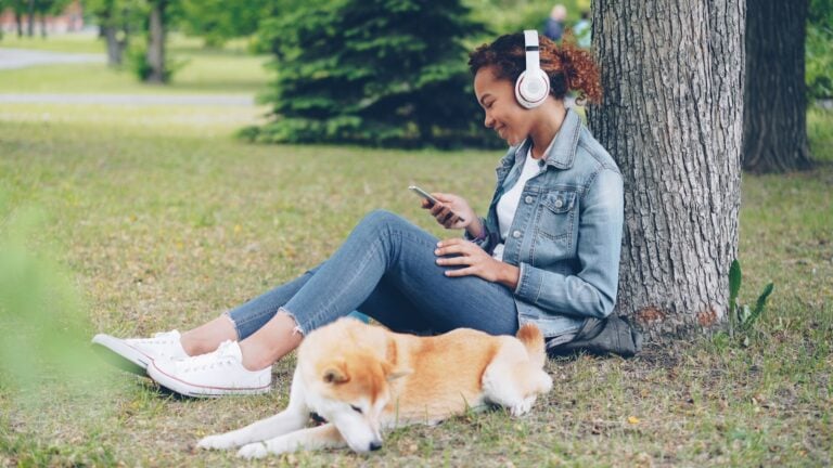 Woman enjoys music in the park with her dog.