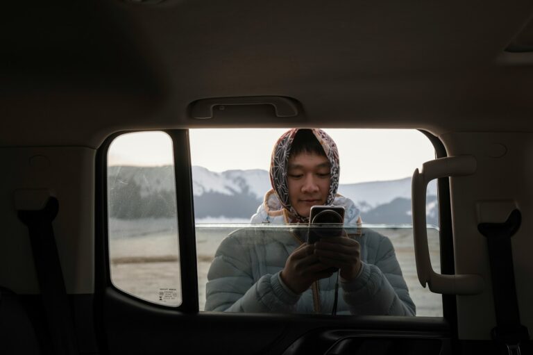 Person using phone in car with snowy mountains outside