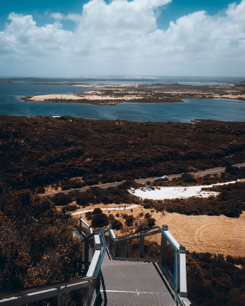 a staircase leading to a beach with a body of water in the background