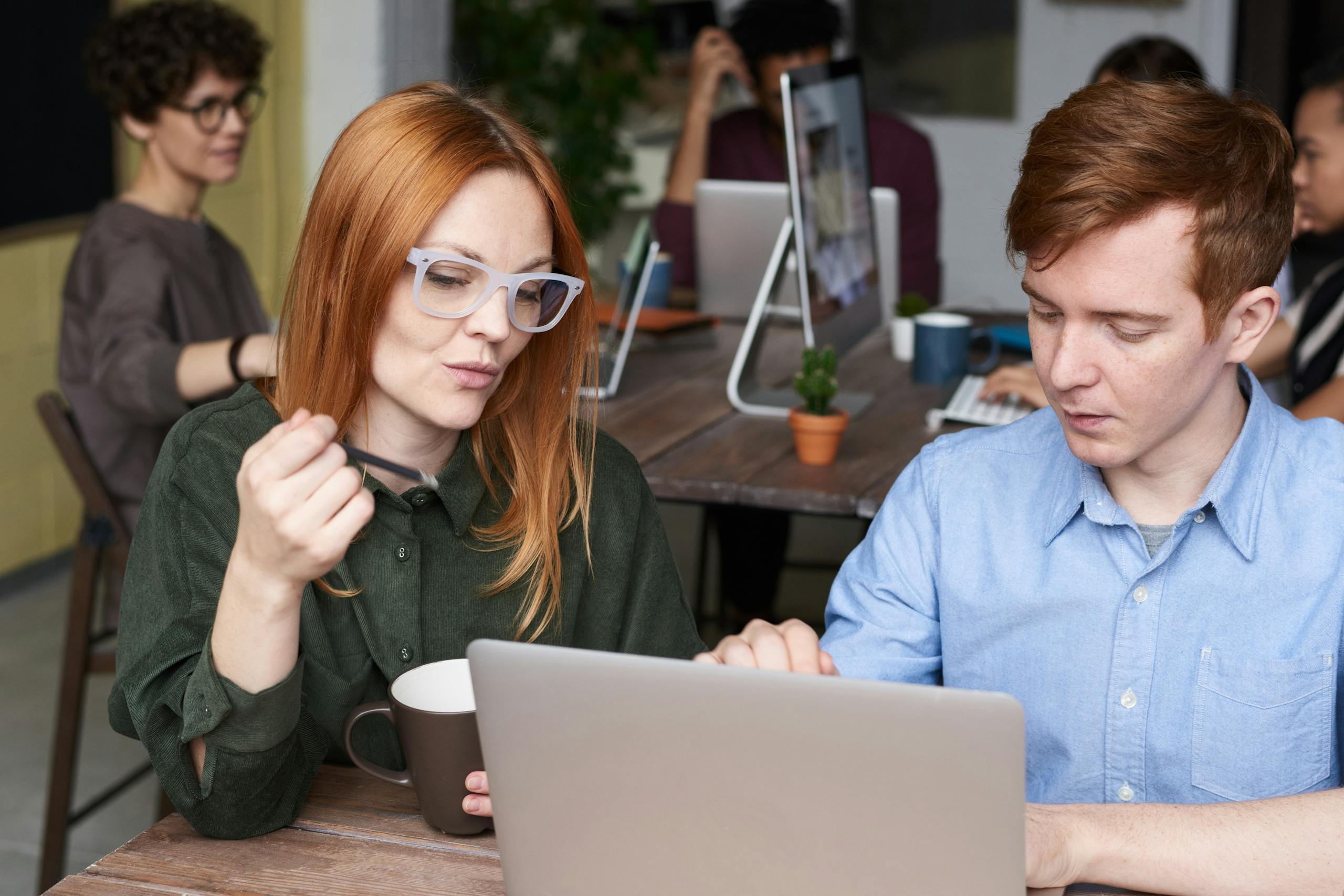 Group of adults collaborating in a modern office with laptops and discussion.