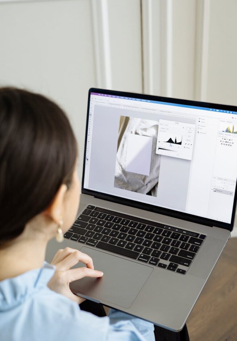 Woman using a laptop editing software to enhance digital images indoors.