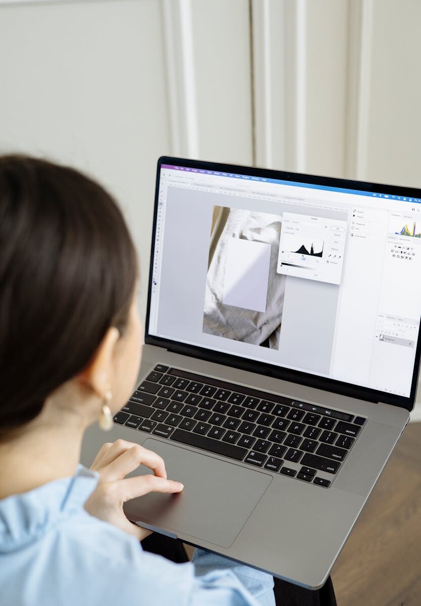 Woman using a laptop editing software to enhance digital images indoors.