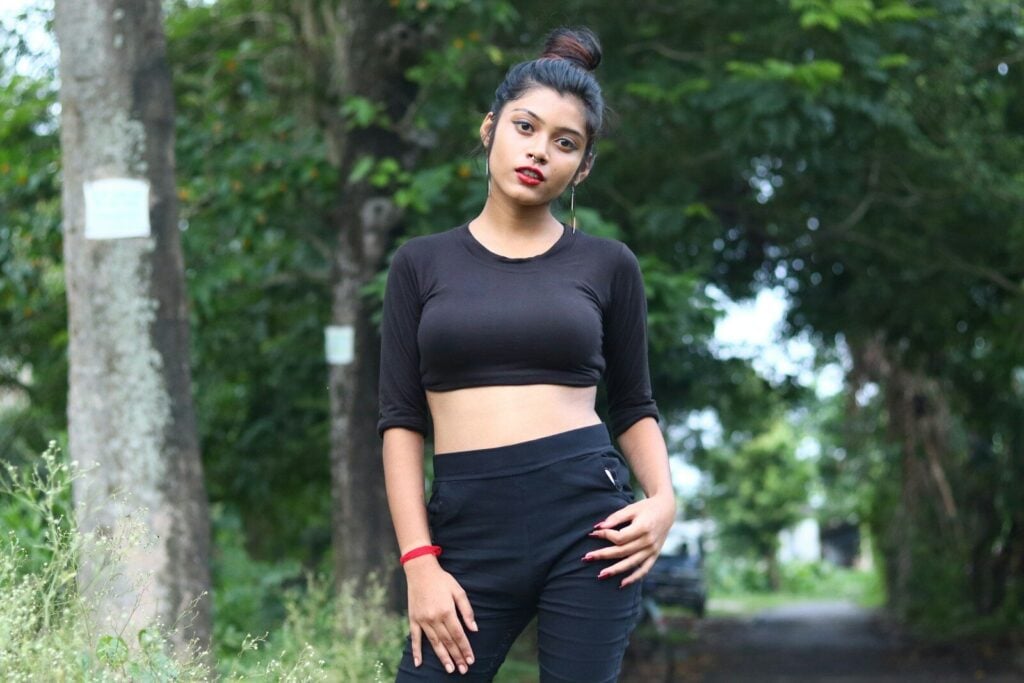 A young woman poses outdoors in a black outfit.