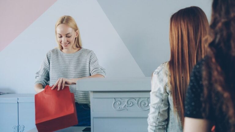 Woman opens a red bag in front of others.