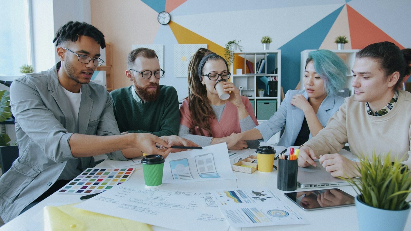 A diverse group of five people collaborating on a design project in a workspace